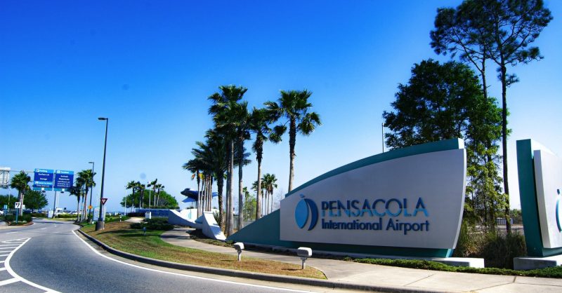 Entrance sign and palm-lined roadway at Pensacola International Airport